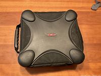 Closed black OXO DVD/CD carrier case with padded corners and a handle on wooden surface