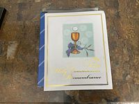 Front cover of the First Communion remembrance book showing a chalice, grapes, and text in gold.