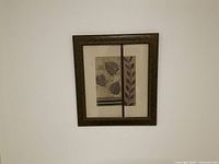 Photo of a framed leaf picture showing the full front view against a white wall.
