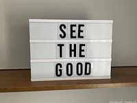 White plastic lightbox message board showing a positive message 'SEE THE GOOD' made with black letters on three rows.