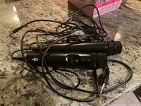 Two black wired handheld microphones lying tangled on granite countertop showing on/off switches and attached cables with 1/4 inch audio plugs.