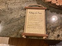 Wooden decorative wall plaque with rope border and printed poem text titled 'Pathway of a Nurse', placed on countertop.