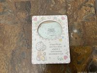 Precious Moments rectangular picture frame with oval photo window and character design on stone background.