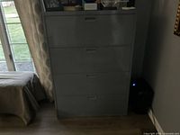 Photo of grey steel file cabinet with four drawers, showing general condition and design