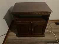 Front view of the dark brown wooden TV stand with closed cabinet doors.
