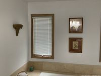 View of two framed wall art scrolls hung on wall near window, showing their size and placement.