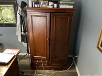 Front view of Arhaus armoire with closed doors, showing wood finish and metal knobs.