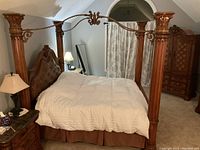 View of the bed from the foot and side, showing carved posts, rope details, and matching bedside furniture.