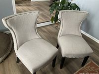 Front view showing beige fabric and nailhead trim on the chairs