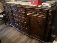 Full view of the dark wood dining cupboard showing carved details, drawers and cabinet doors