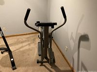 Front view of elliptical trainer emphasizing dual handle grips and pedal mechanism.