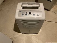 Photo showing front view of white GE humidifier with control panel on top and vent grills on front.