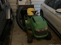 Front three-quarter view of green and yellow John Deere riding tractor indoors