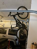 Side view of black full suspension mountain bike hung on garage rack