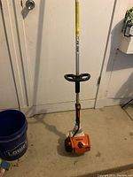 Front view of the weed trimmer showing engine housing, straight shaft, throttle control and loop handle.