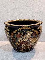 Front view of black flower pot with gold floral and bird (crane) design.