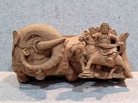 Full side view of the carved wooden sculpture showing the warrior on horse with elephant behind.