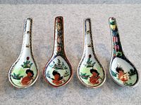 Four antique Chinese porcelain spoons with rooster and floral motifs placed side by side on a neutral background.