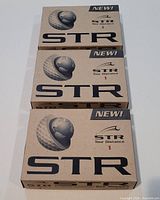 Photo showing 3 unopened boxes of STR Tour Distance golf balls, each box labeled with branding and marked as new.
