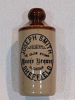 Full frontal view of beige stoneware bottle with brown top. Text on bottle reads "Joseph Smith Ye Olde Stone Beere Brewery Sheffield."