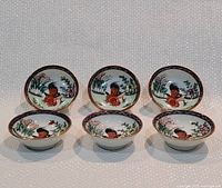 Six small white porcelain cups arranged in two rows, showing the colorful rooster and floral motif painted on the inside surface.