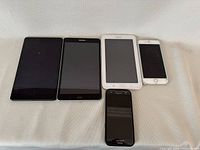 All five devices arranged on a white surface showing size variation and condition.