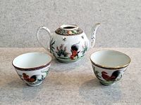 Full tea set showing two cups and teapot with rooster decoration