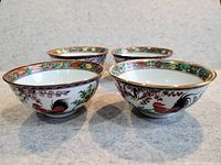 Four medium-sized Chinese porcelain bowls, each painted with rooster motifs and colorful floral borders arranged in two rows, showing consistent design and good condition.