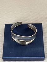 Top-down view of the vintage sterling silver cuff bracelet showing its smooth polished surface and open cuff design, placed on a blue box.