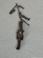 Brooch laid flat showing the full length and detail of the music themed charms including saxophone, trumpet, clarinet, and drum