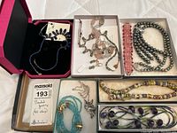 Lot of assorted beaded jewelry displayed in several boxes including multiple necklaces with various beads and a wolf head pendant.