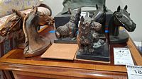 Top view of the two dog and four horse head bookends on a wooden surface showing all six pieces together.