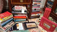 Overview of multiple stacked books on floor and bedside cabinet