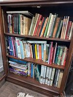 Three-shelf wooden bookcase filled with assorted books on animal subjects