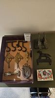 Full lot overview showing brass horse head hooks, horseshoe doorknocker, metal figure, and card