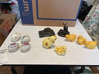 All items shown on a table including the ceramic chicks, egg trinket boxes, and metal bunnies.