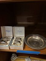 Six sterling silver napkin rings in two white satin-lined boxes with Gorham branding, plus one sterling silver bowl with decorative edge.