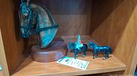 All three items on shelf: horse head bust, soldier on horse, separate horse