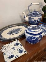 Photo of entire lot showing Spode platter, Staffordshire teapot, Delft canister, and Delft trivet with blue and white patterns