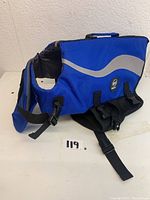 Blue dog body harness with adjustable straps and buckles showing EMUST brand patch and reflective design