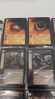 Four close-up cards displayed in protective sleeves featuring The One Ring and characters/events from The Lord of the Rings card game.