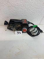 Front and side view of the Skil Sand Cat belt sander with attached power cord and model number plate visible.