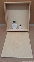Wooden keepsake box with the 6 ml and 30 ml Pure Alfred Sung perfume bottles inside, box lid with branding laid in front.