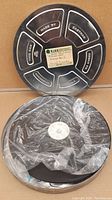 Two metal 32mm film reels stacked with film wrapped in plastic covering
