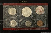 Front side showing 5 US coins enclosed in blister pack labeled with 'OCEAN'. Coins visible are half dollar, quarter, dime, nickel, and penny with 40% silver content. Bureau of the Mint label included.