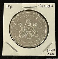 Reverse side of the 1971 Canadian silver 1 dollar coin showing British Columbia coat of arms and commemorative text.