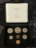 Photo of the set inside a Royal Canadian Mint white presentation case with gold lettering, coins on black velvet background