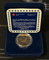 Loonie coin displayed inside blue velvet display case with information card from Royal Canadian Mint