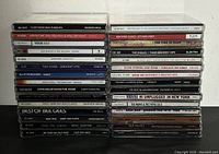 Front view of stacked music CD jewel cases showing titles of rock and related genre albums.