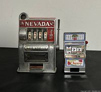 Front view of both miniature slot machine banks, displaying details and design.